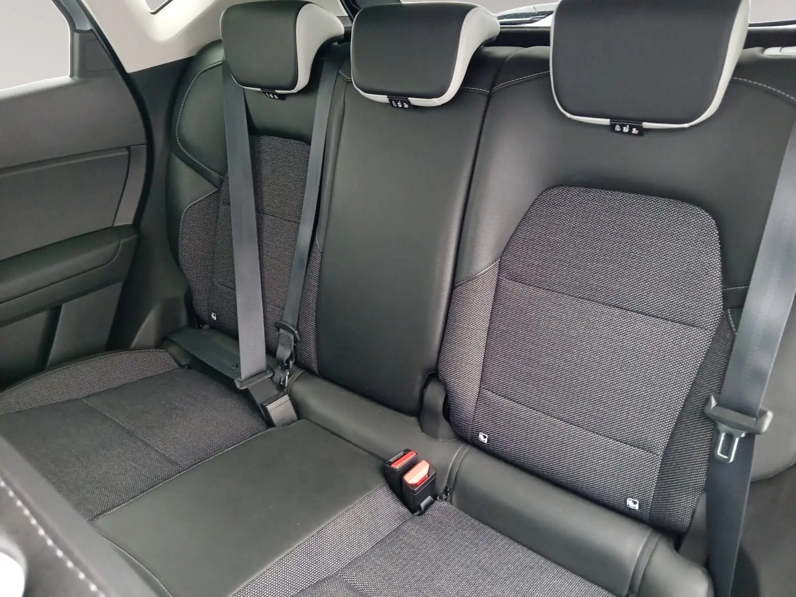 Vue intérieure de la banquette arrière du Renault Captur gris alu/noir 2023, avec sièges en tissu et cuir noir.
