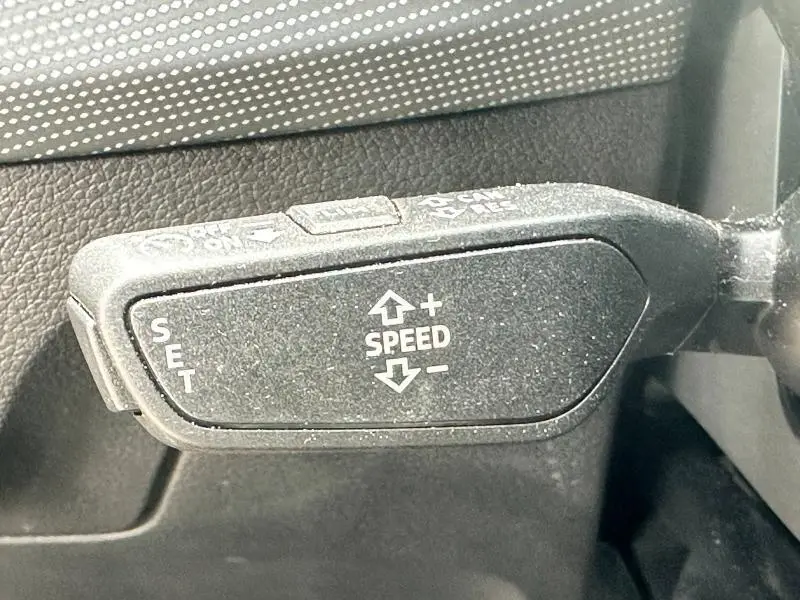 Gros plan sur la commande de régulateur de vitesse du volant d'un Audi Q2 30 TDI gris Daytona nacré 2024.