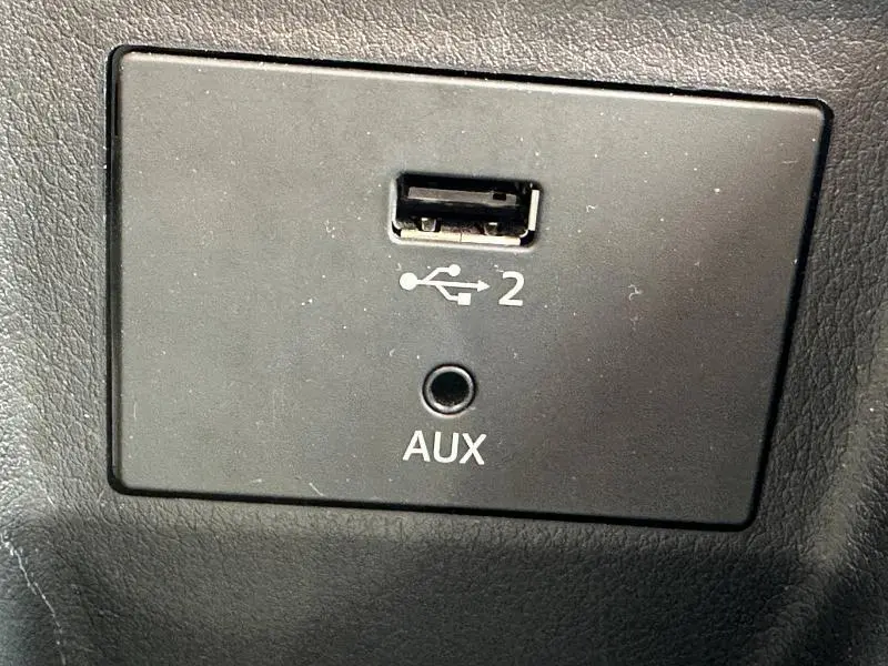 Gros plan sur la prise USB et AUX noire intégrée dans l'habitacle du Audi Q2 30 TDI gris Daytona nacré 2024.