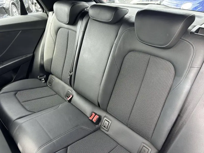 Vue intérieure sur la banquette arrière en cuir noir de l'Audi Q2 30 TDI S line 2024, avec appuie-têtes et ceintures visibles.