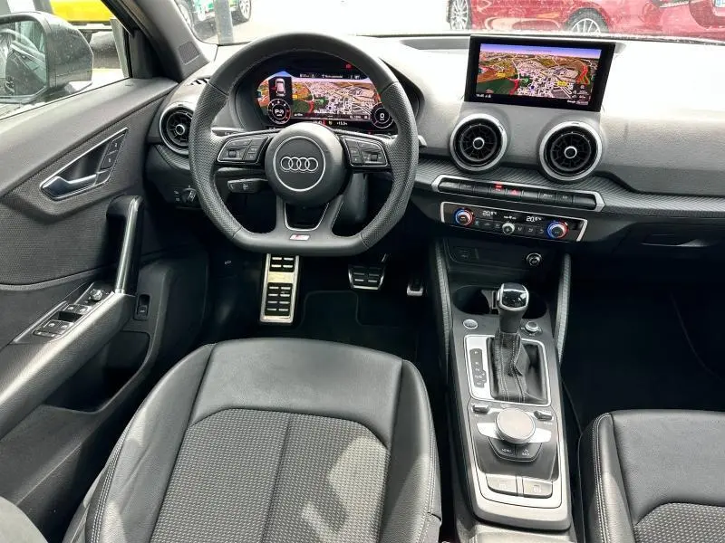 Vue intérieure avant de l'Audi Q2 30 TDI S line 2024 avec tableau de bord numérique et écran central GPS couleur.