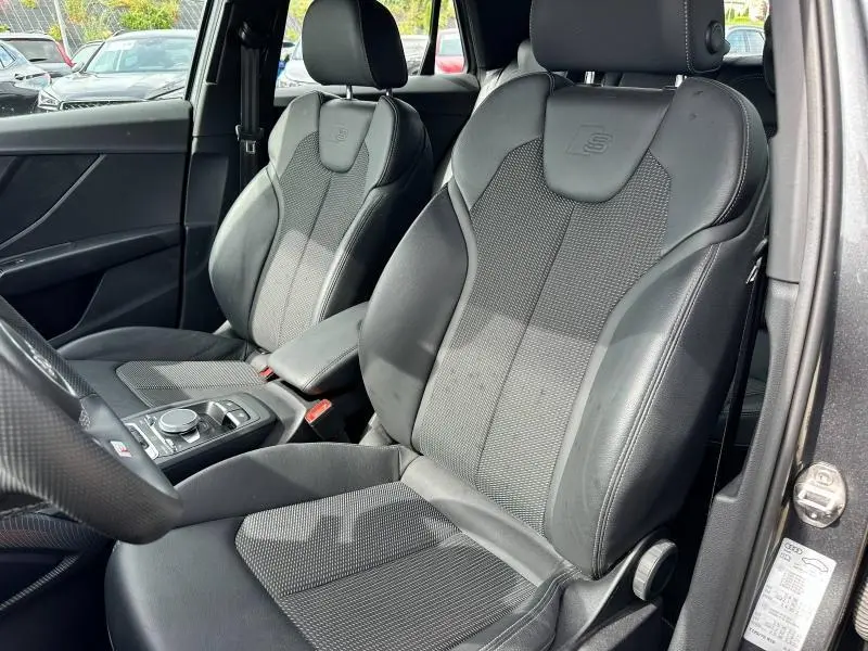 Vue rapprochée des sièges avant sport noirs avec logo S embossé de l'Audi Q2 30 TDI S line 2024 en intérieur.