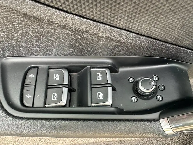 Commandes électriques des vitres et réglage des rétroviseurs côté conducteur d'un Audi Q2 gris Daytona nacré 2024 S line.