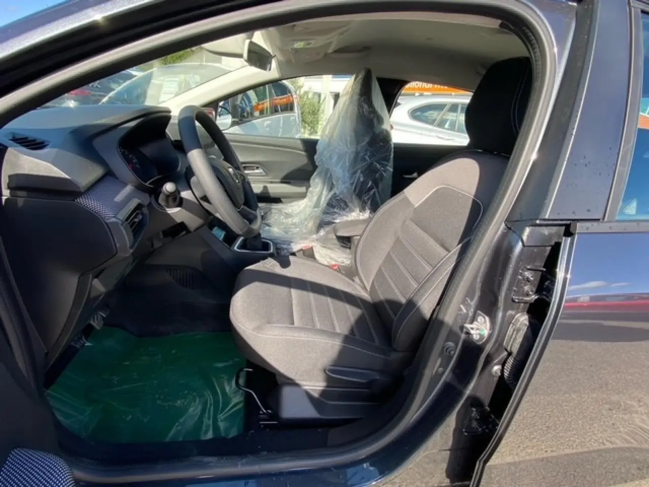 Intérieur côté conducteur de la Dacia Logan gris 2022, montrant le siège avant et le tableau de bord moderne.