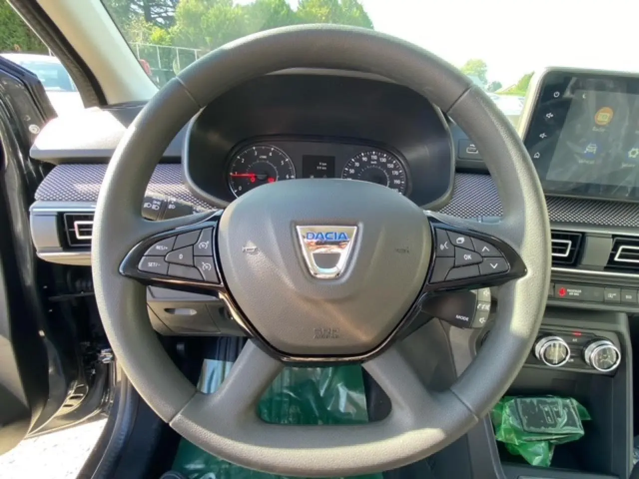 Vue rapprochée du volant gris de la Dacia Logan 2022 avec commandes intégrées et tableau de bord visible.