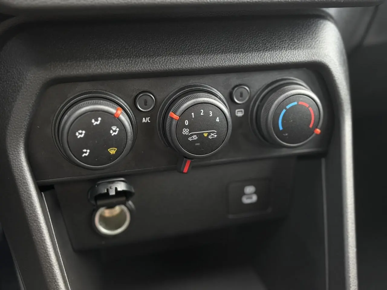 Gros plan sur les commandes de climatisation manuelle du tableau de bord du Dacia Sandero Stepway Bleu Iron 2025.