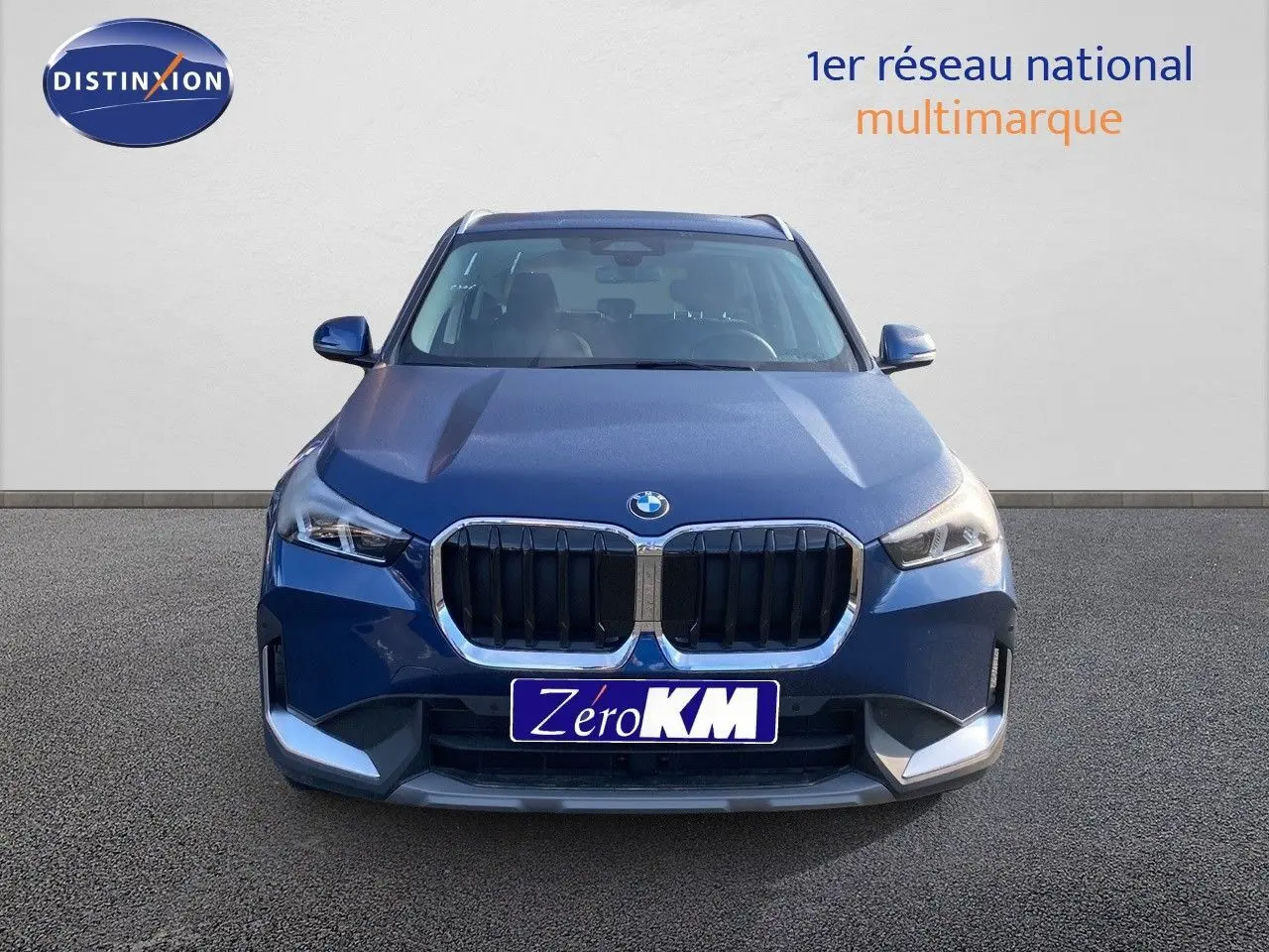 BMW X1 18I 136CH bleu Phytonic Metal vue de face avec calandre imposante et phares LED allumés