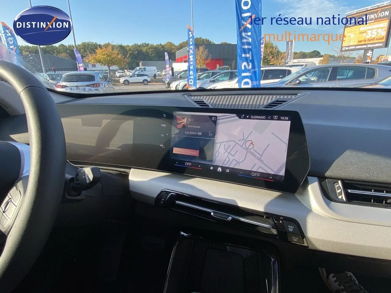 Vue intérieure du tableau de bord du BMW X1 18I 2024 avec écran tactile affichant la navigation et la radio.