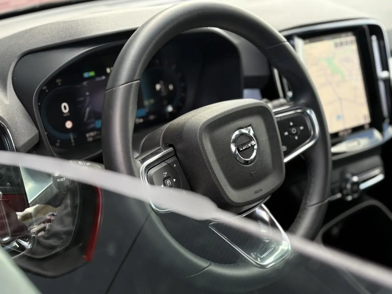 Vue rapprochée du volant noir du Volvo XC40 avec tableau de bord digital et écran tactile de navigation visible.