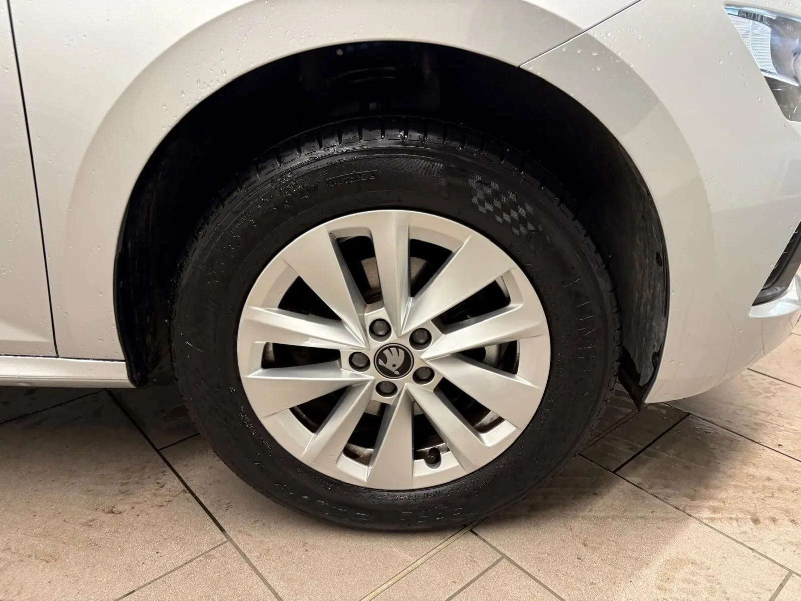 Gros plan sur la roue avant droite d’un Skoda Kamiq gris argent 2025 avec jante alliage et logo Skoda central.