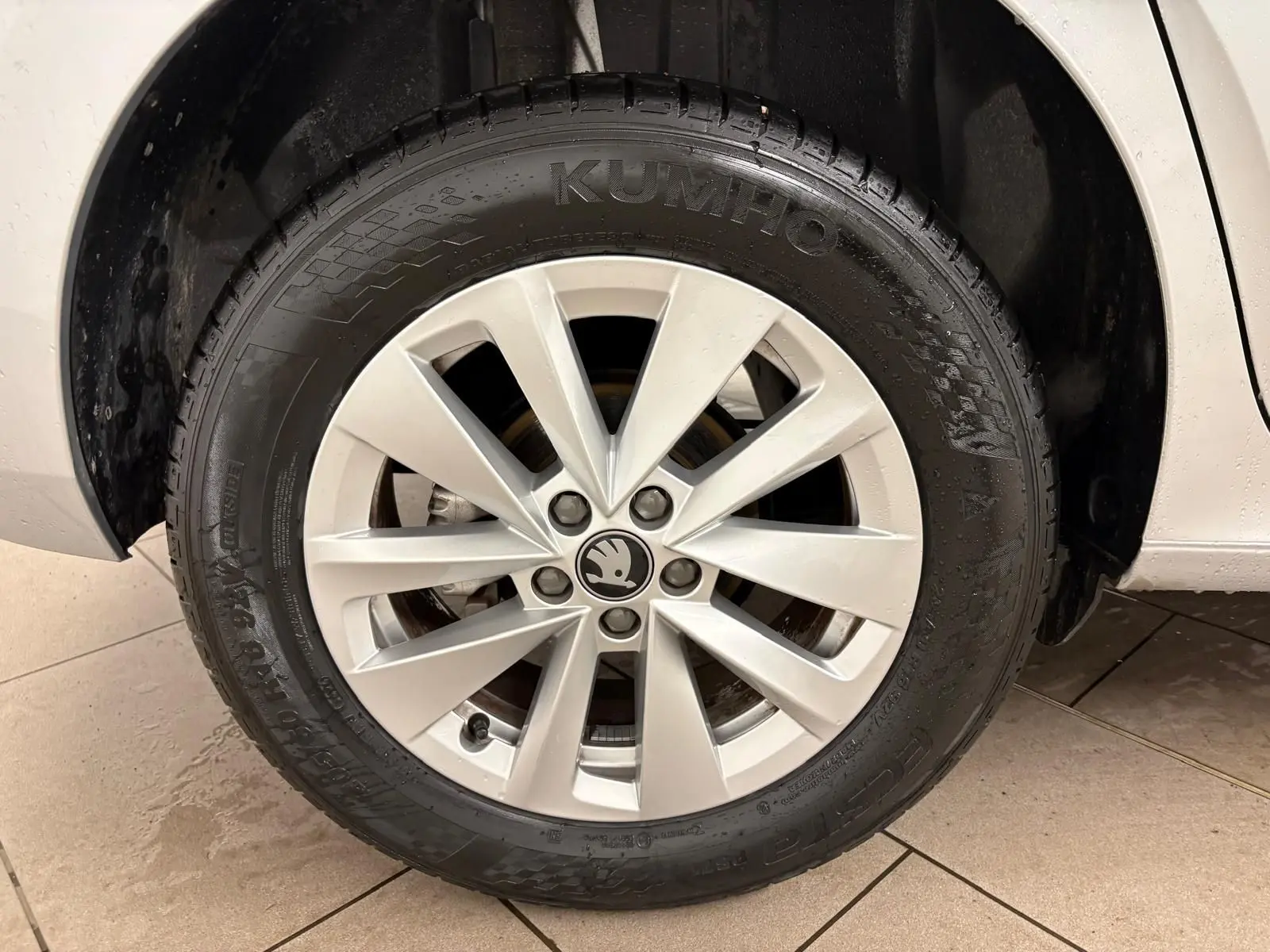 Gros plan sur la roue avant droite du Skoda Kamiq gris argent avec jante alliage et logo central visible.