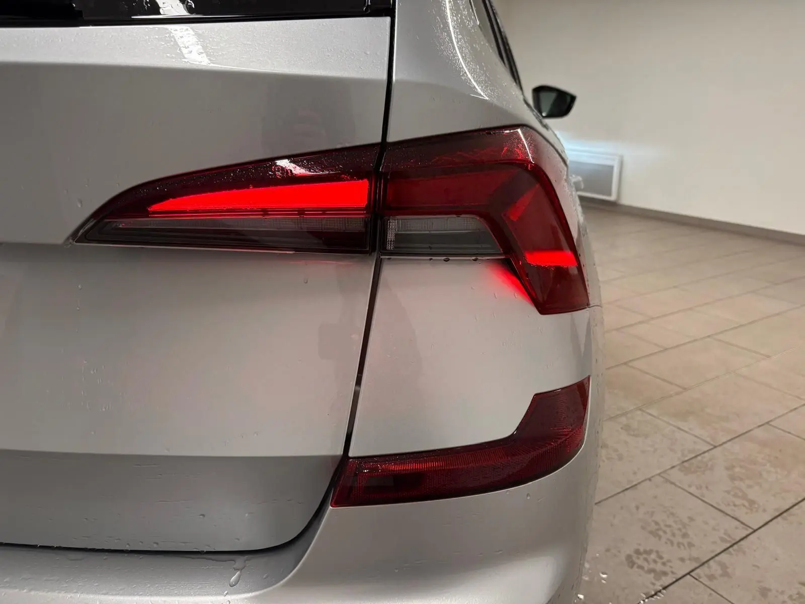 Gros plan sur le feu arrière droit allumé d’un Skoda Kamiq gris argent 2025 avec peinture métallisée.