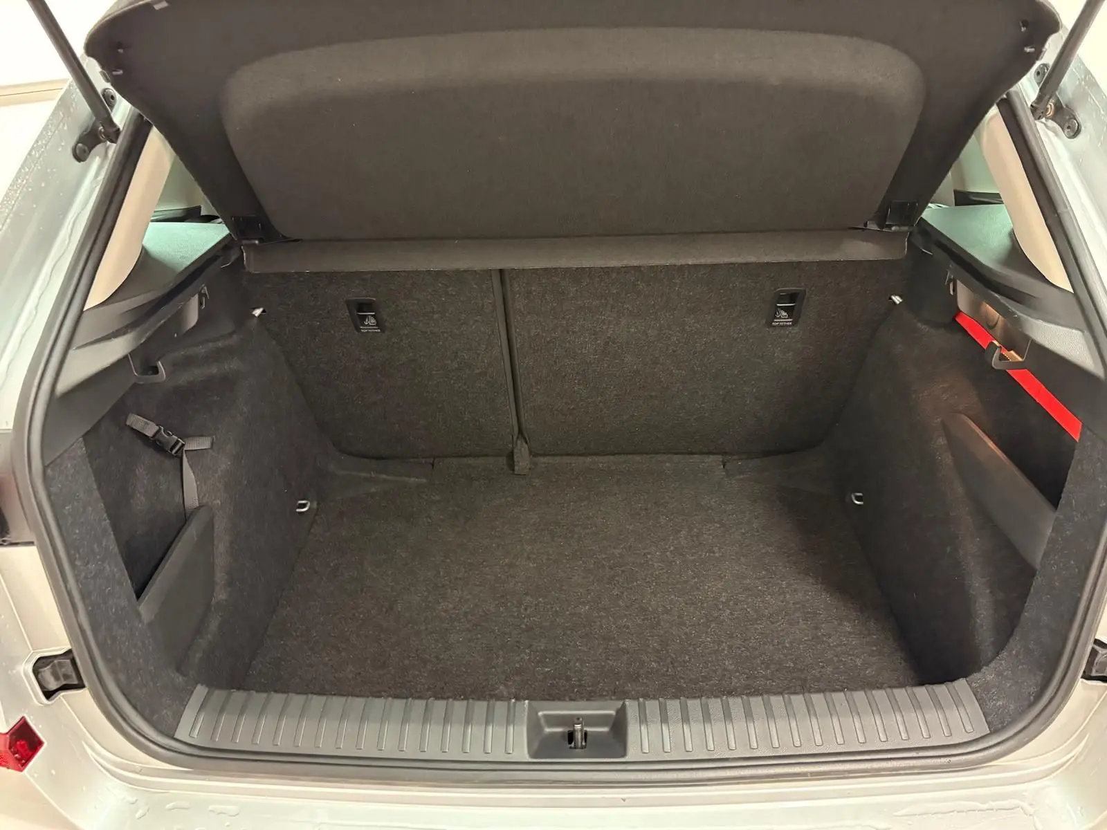 Coffre ouvert d’un Skoda Kamiq gris argent 2025, montrant un espace de chargement propre et bien agencé.