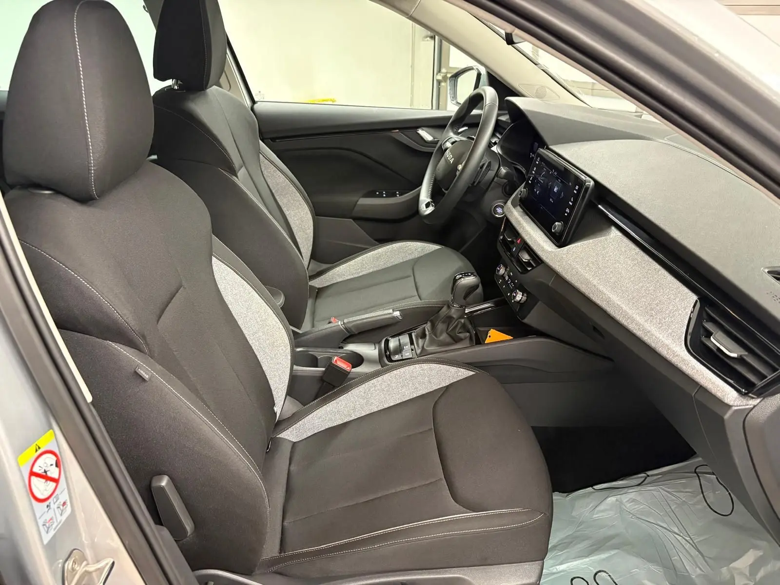 Vue intérieure côté conducteur du Skoda Kamiq gris argent 2025, avec sièges bi-tons et tableau de bord moderne.