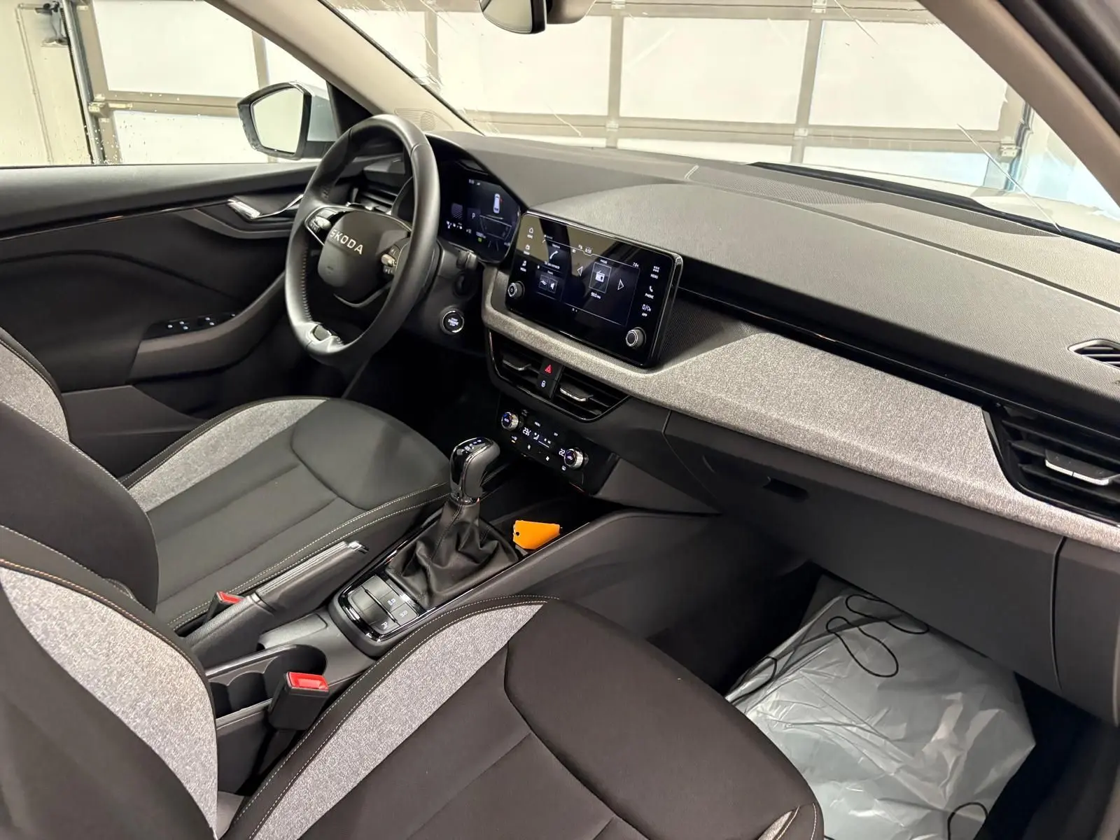 Vue intérieure côté conducteur du Skoda Kamiq 2025, mettant en valeur la console centrale avec boîte auto et écran tactile.