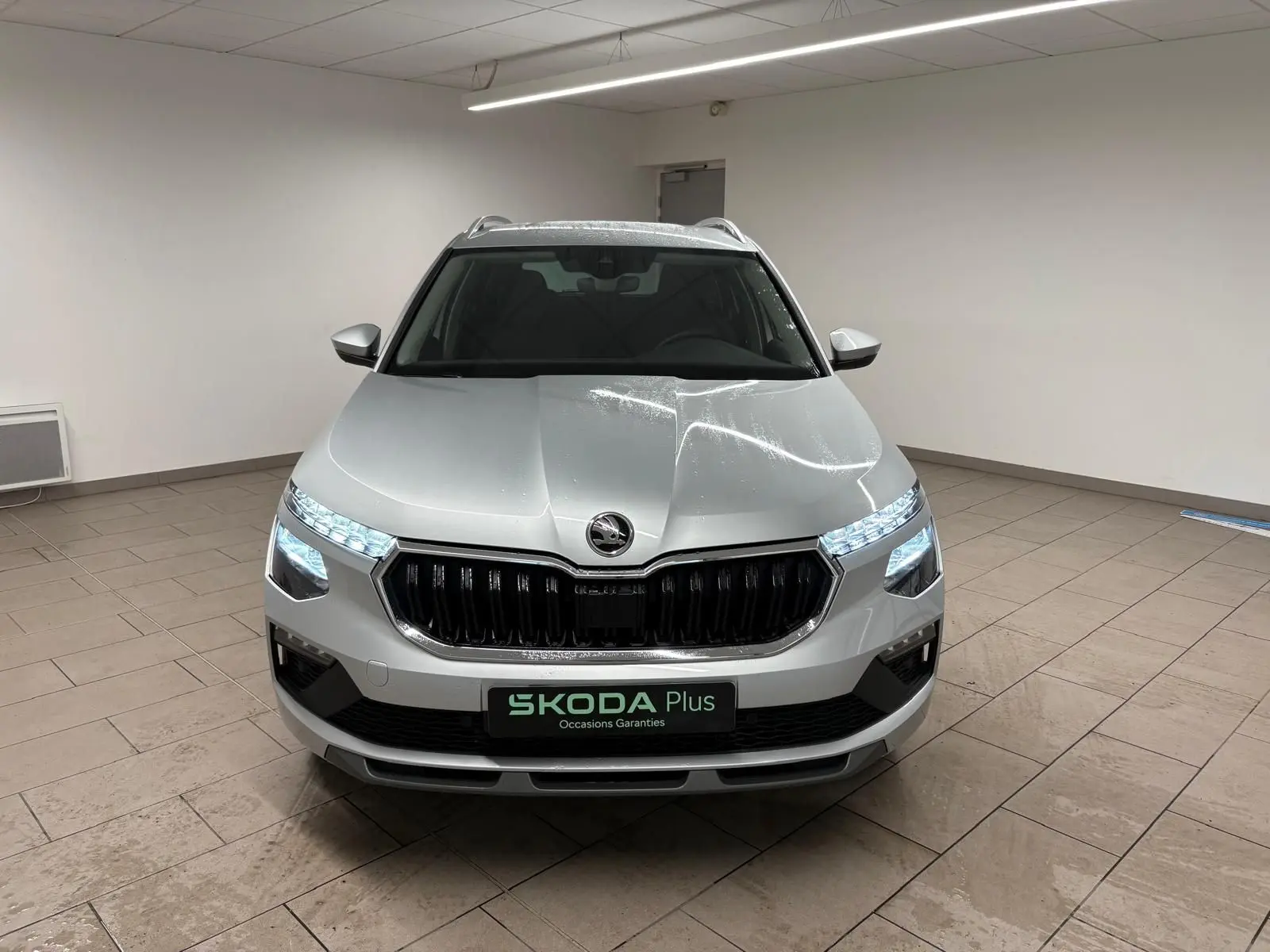 Vue avant frontale du Skoda Kamiq gris argent avec phares LED allumés et calandre noire brillante.