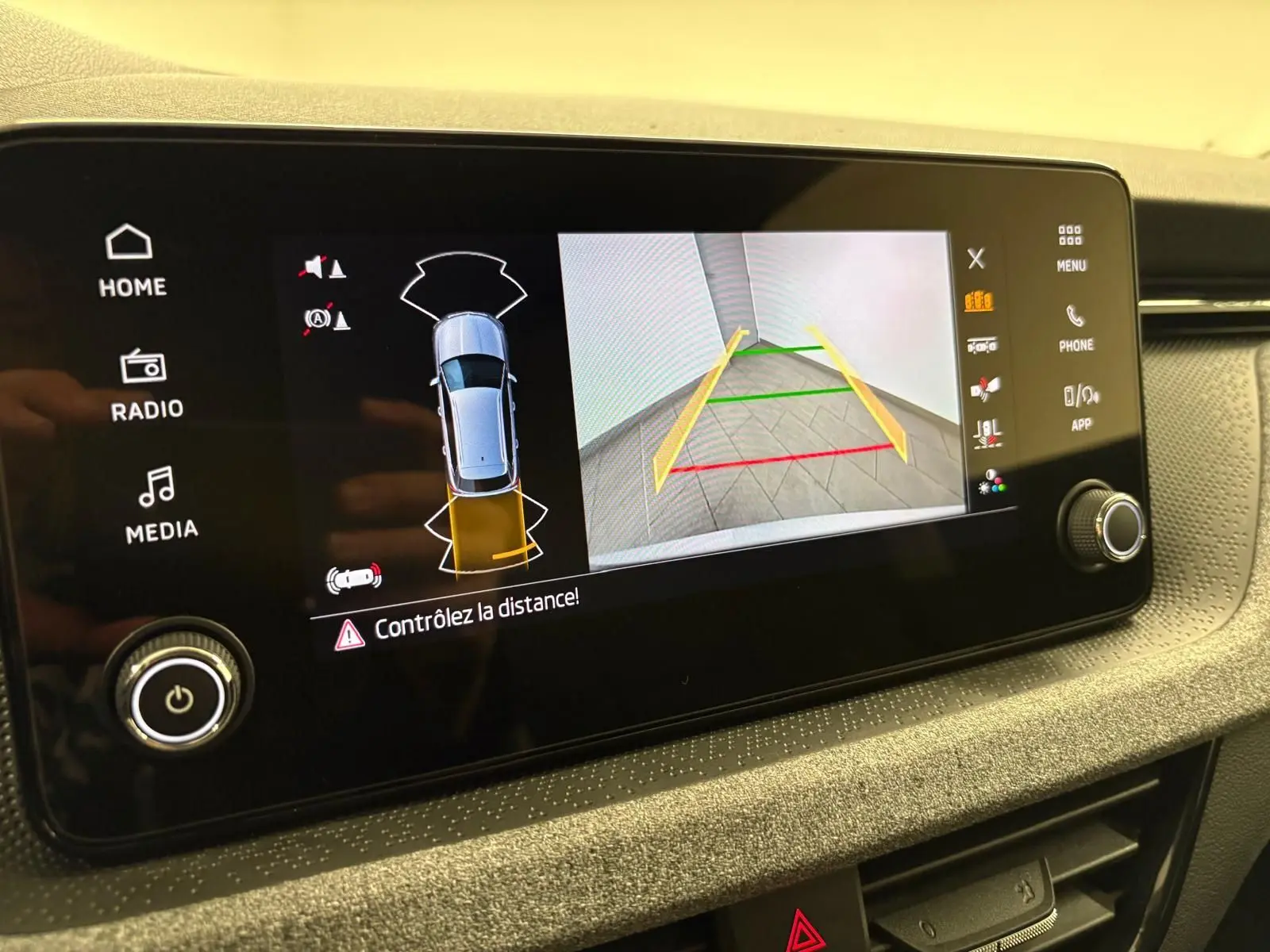 Écran multimédia affichant la caméra de recul et l'alerte de distance du Skoda Kamiq gris argent, vue intérieure du tableau de bord.