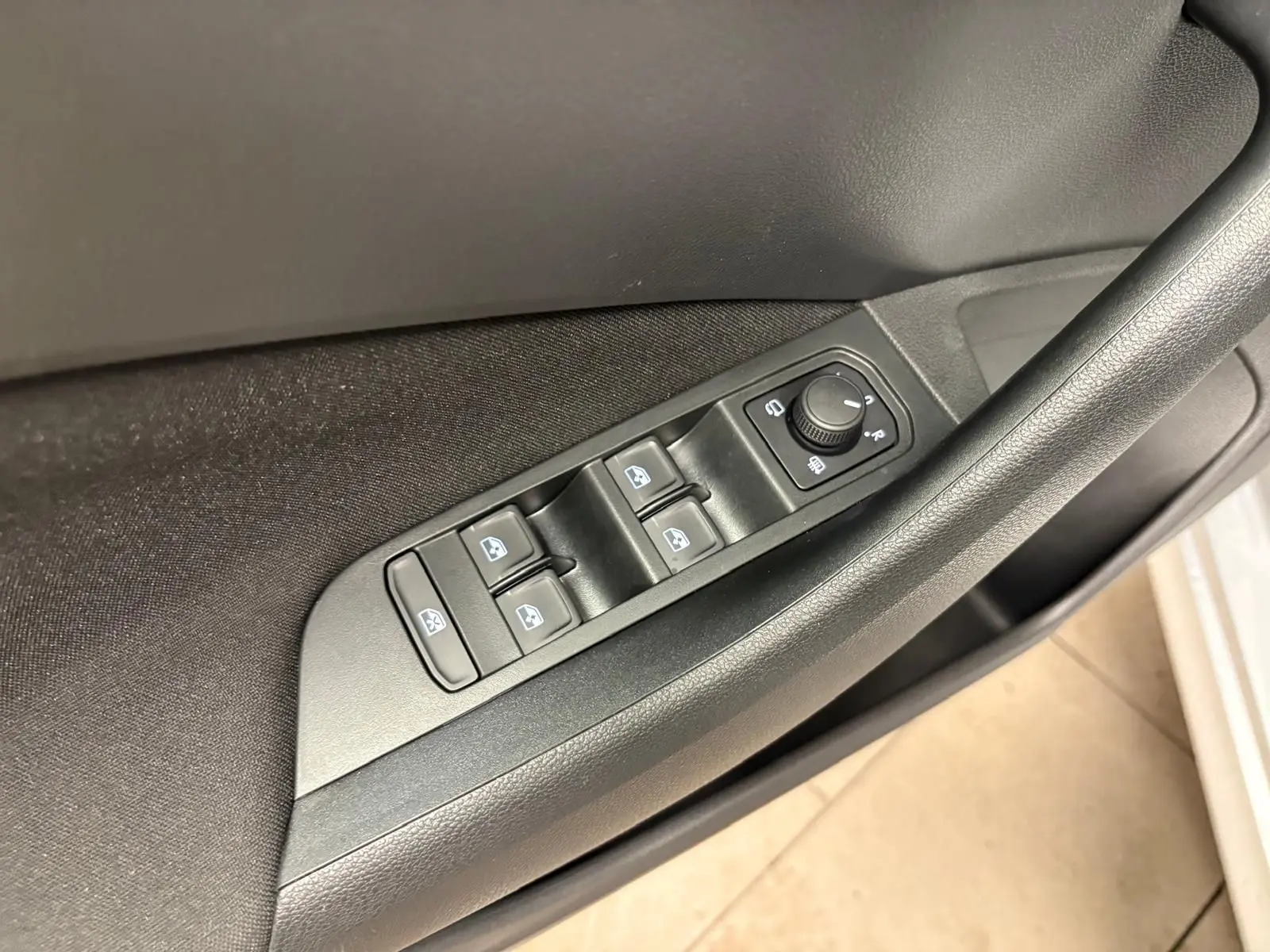 Gros plan sur les commandes des vitres et des rétroviseurs côté conducteur d’un Skoda Kamiq gris argent 2025.