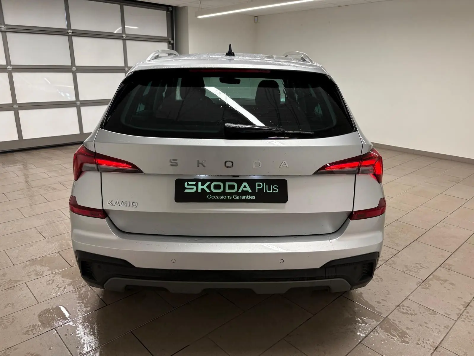 Vue arrière d'un Skoda Kamiq gris argent 2025 avec feux LED et caméra de recul visible sur le pare-chocs.