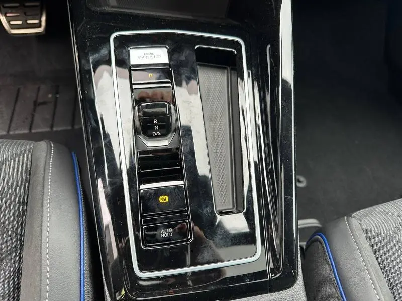 Vue rapprochée de la console centrale noire brillante avec sélecteur de boîte auto et bouton start/stop d’une Volkswagen Golf gris 2.0 TDI R-Line.