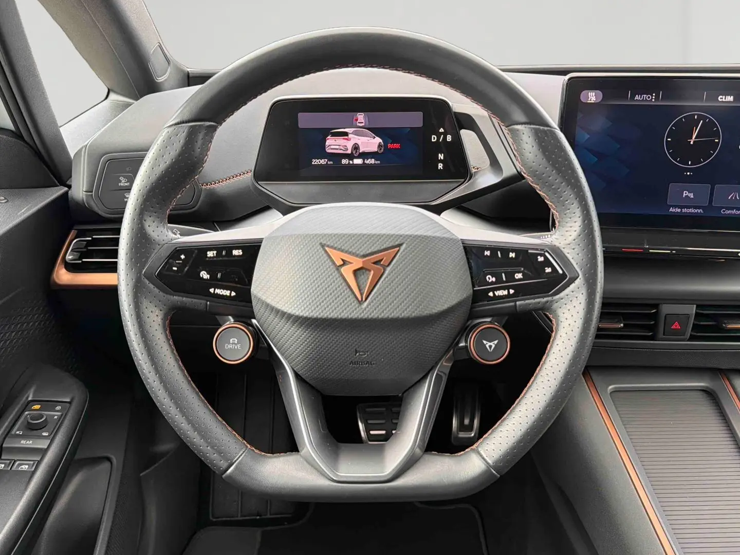 Vue rapprochée du volant multifonction noir et gris avec logo CUPRA cuivré du tableau de bord du CUPRA Born blanc électrique 2024.