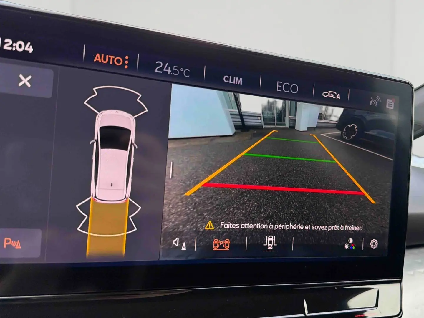 Écran tactile du CUPRA Born blanc montrant la caméra de recul avec guidage coloré et alertes de sécurité.