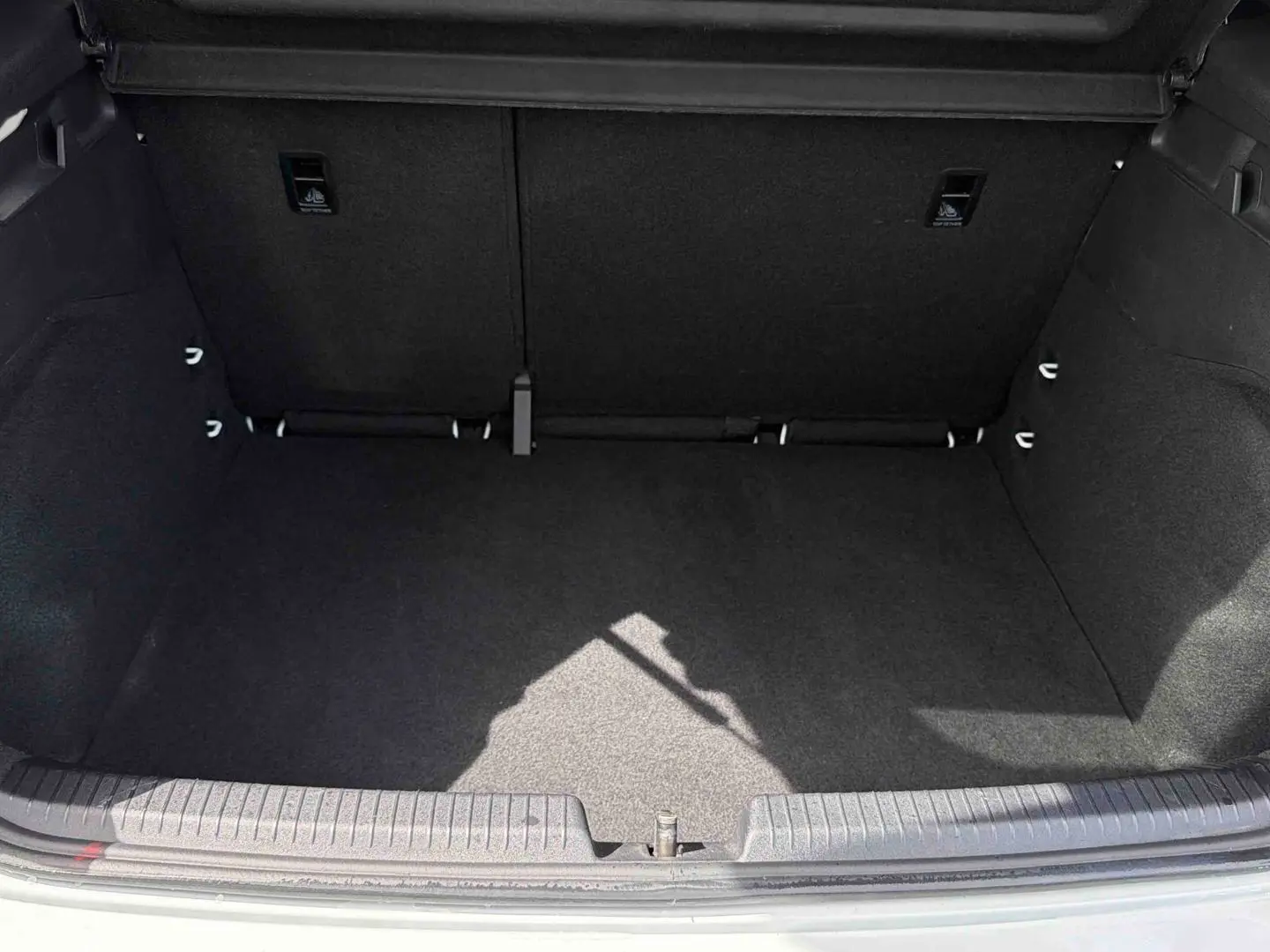Coffre ouvert vu de face d'une CUPRA Born blanche 2024, montrant un espace de chargement vide et propre.