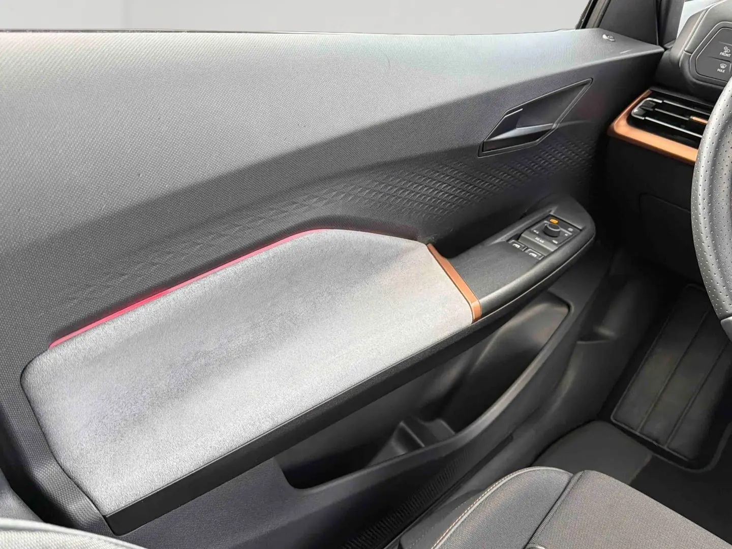 Vue intérieure côté gauche de la porte avant du CUPRA Born 2024 avec garniture grise et détails cuivrés.