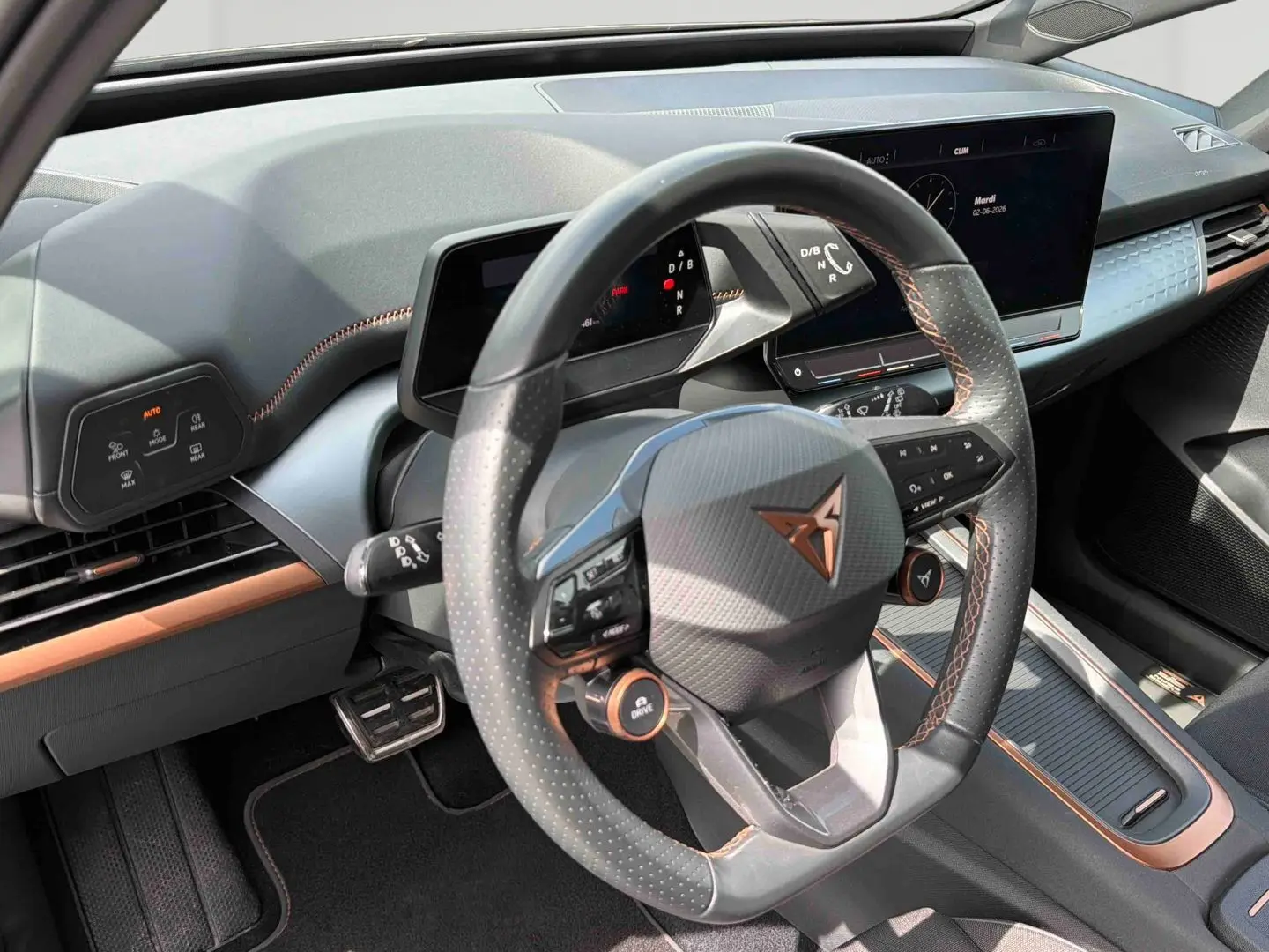 Vue intérieure centrée sur le volant multifonction noir avec surpiqûres cuivre du CUPRA Born 2024.