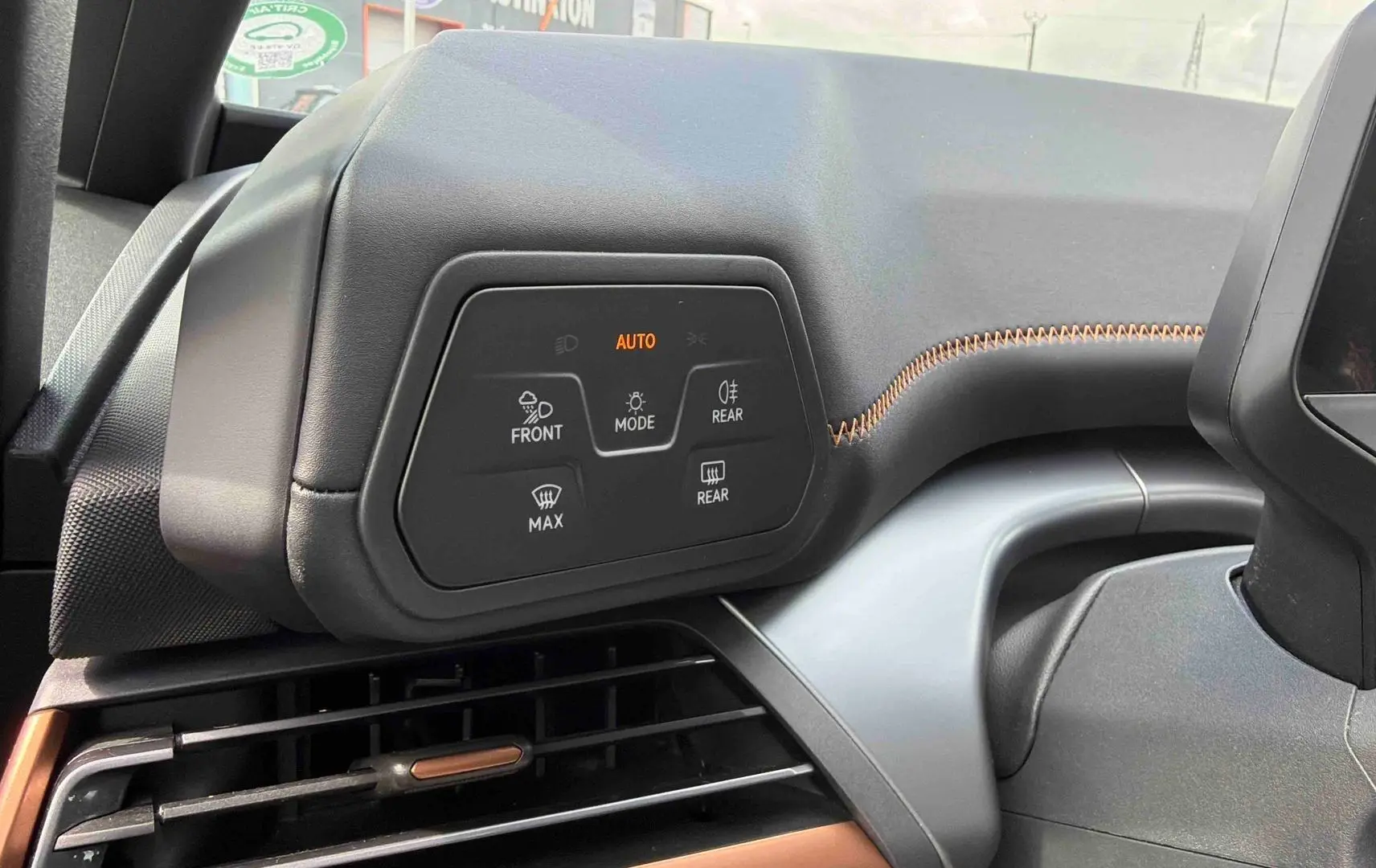 Détail du tableau de bord côté gauche du CUPRA Born blanc 2024 avec commandes d’éclairage et surpiqûres orange.