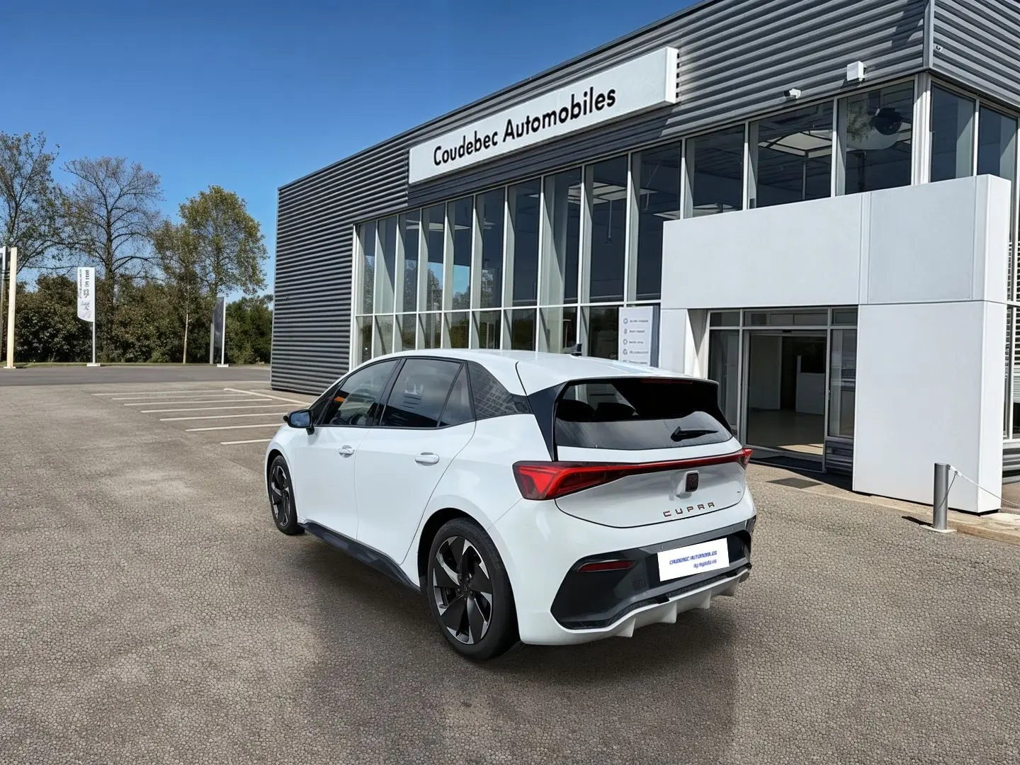 Vue 3/4 arrière d'une CUPRA Born blanche avec jantes Typhoon Black, feux LED et vitres arrière surteintées.