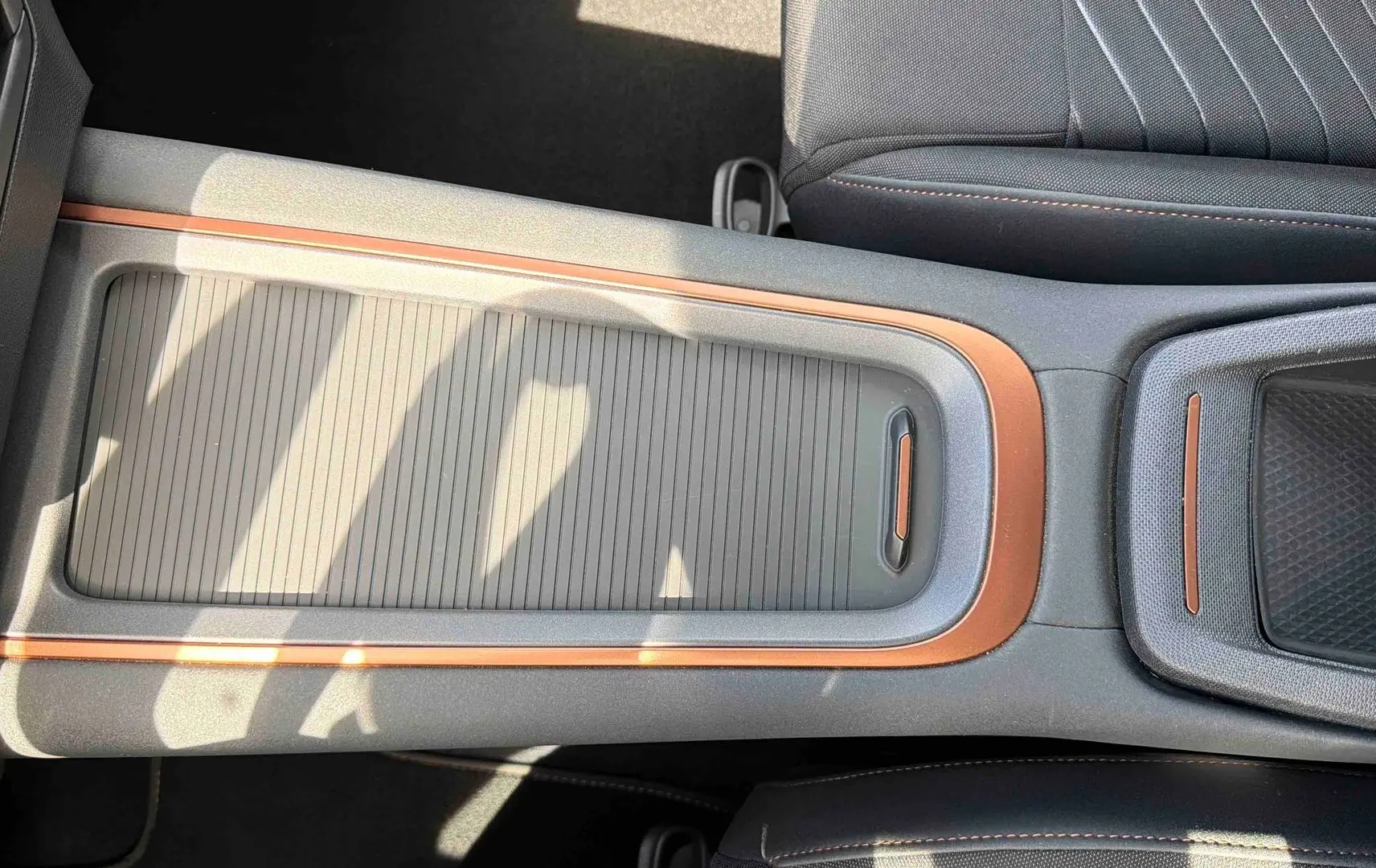 Vue plongeante sur la console centrale du CUPRA Born blanc, avec insertions cuivre et rangement coulissant fermé.