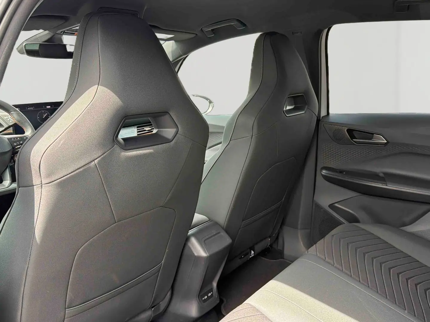 Vue intérieure arrière du CUPRA Born 2024 montrant les sièges avant sport gris et la banquette arrière côté droit.