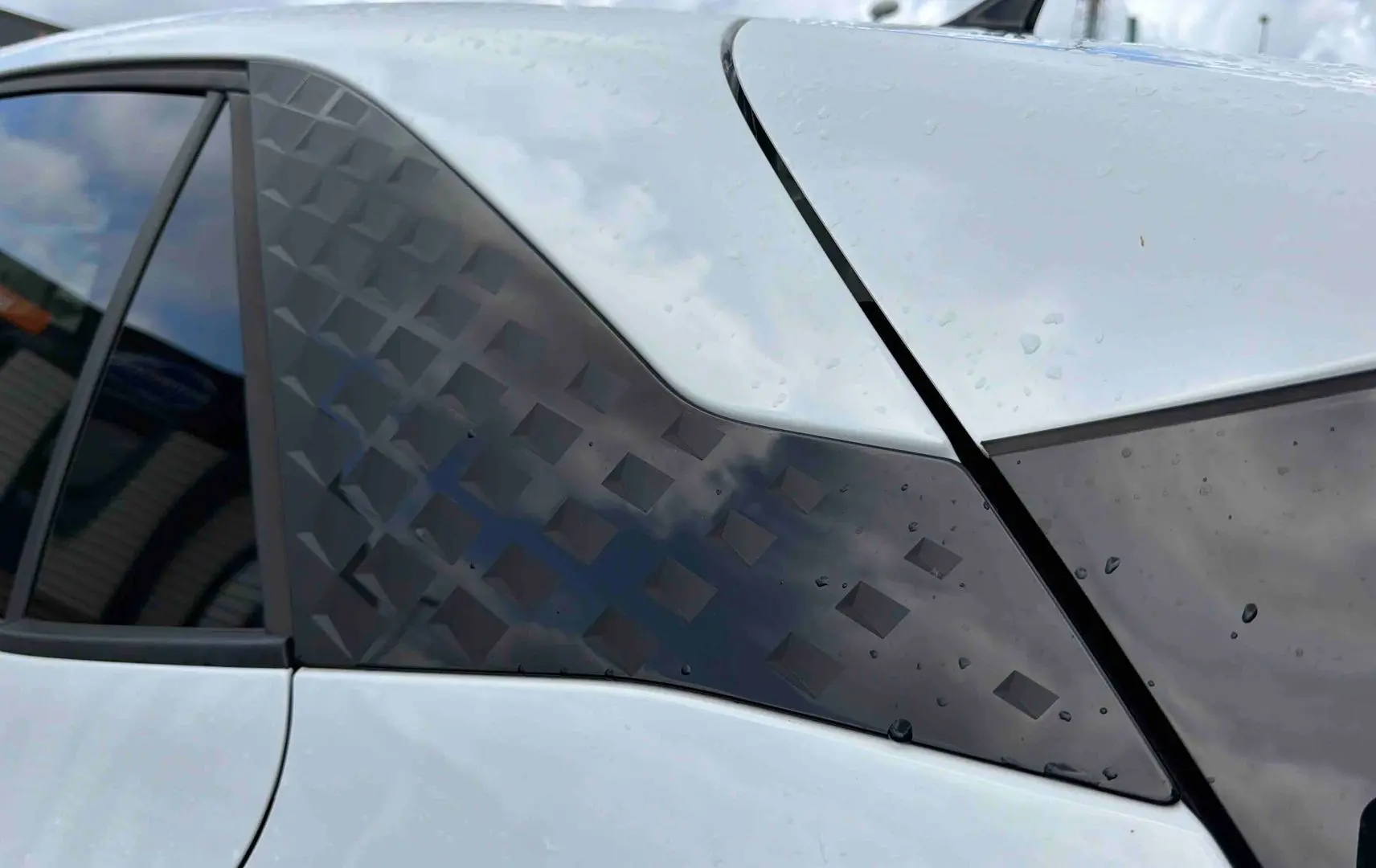 Détail du montant arrière droit blanc du CUPRA Born 2024 avec motif géométrique noir et vitre teintée.