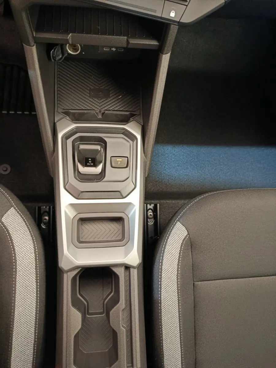 Vue plongeante sur la console centrale du Dacia Duster noir 2026, avec levier de vitesse automatique et sièges tissu gris.
