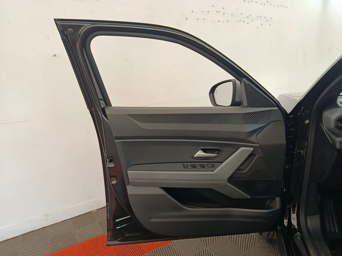 Portière avant gauche ouverte d'un Dacia Duster Journey Hybrid 155 noir, montrant les commandes de vitres et le miroir extérieur.