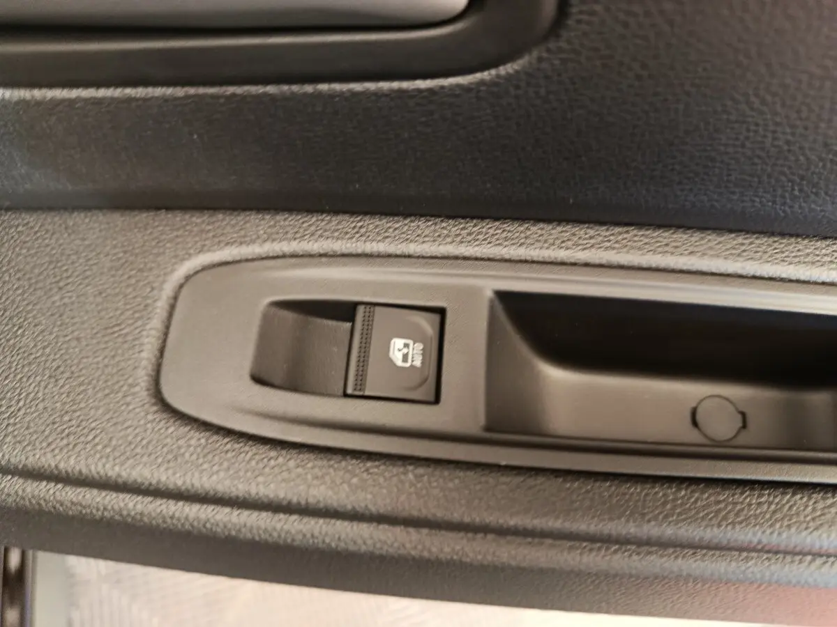 Gros plan sur le bouton de commande de la vitre électrique côté porte intérieure d’un Dacia Duster noir.