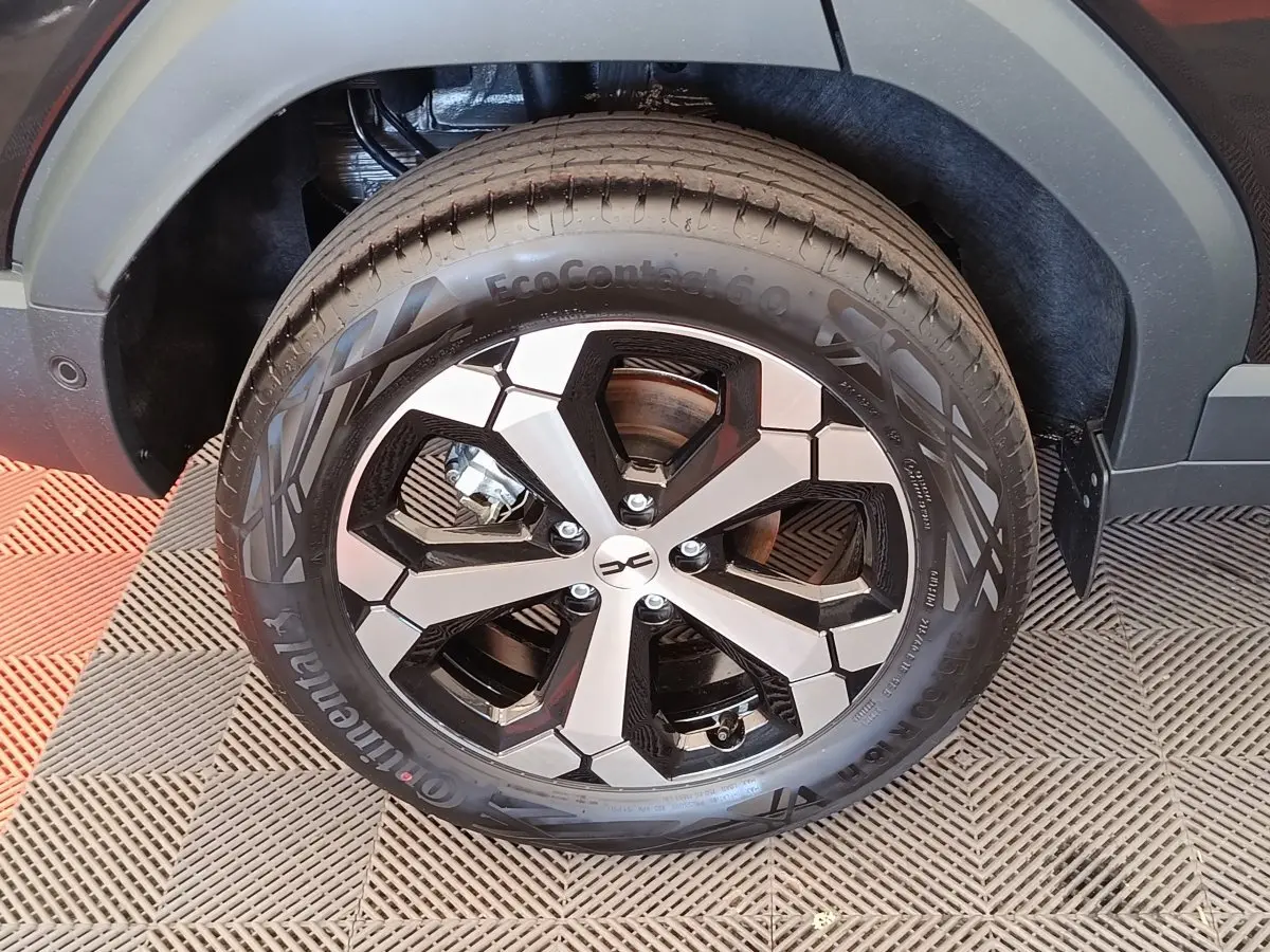 Gros plan sur la roue avant droite du Dacia Duster noir 2026, mettant en valeur la jante alliage bicolore au design moderne.