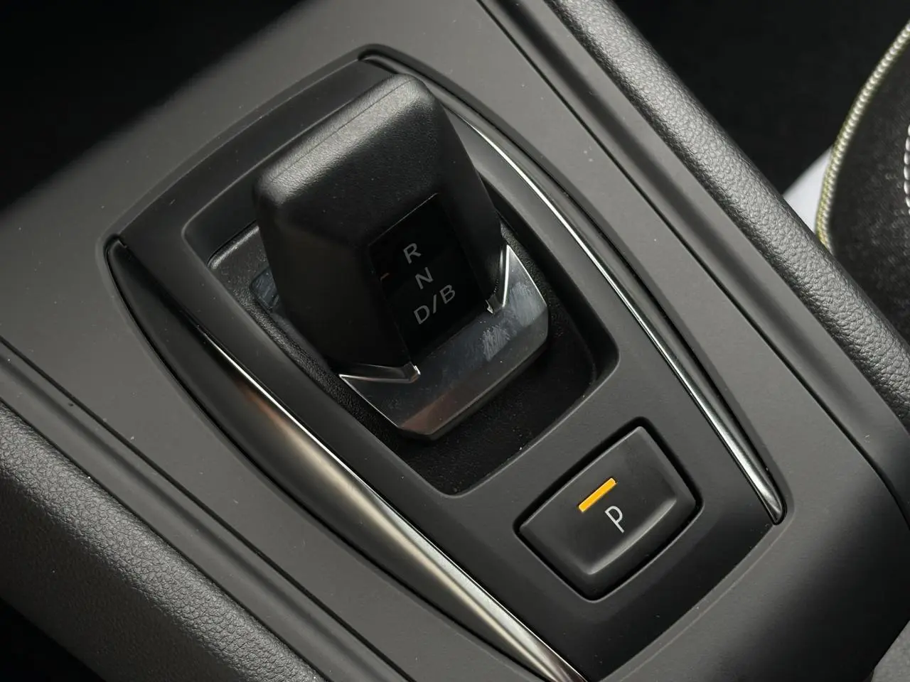 Gros plan sur le levier de vitesses automatique noir et la commande de frein de parking électrique dans l'habitacle du Renault Captur blanc nacré.