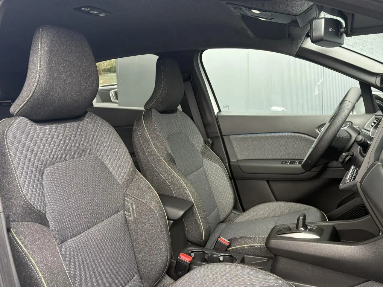 Vue intérieure côté droit du Renault Captur 2026, sièges tissu gris avec console centrale et volant textile.