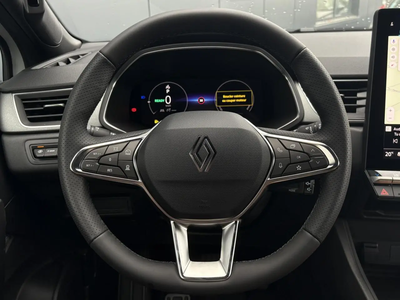 Vue rapprochée du volant noir perforé du Renault Captur 2026 avec tableau de bord numérique et écran tactile latéral.