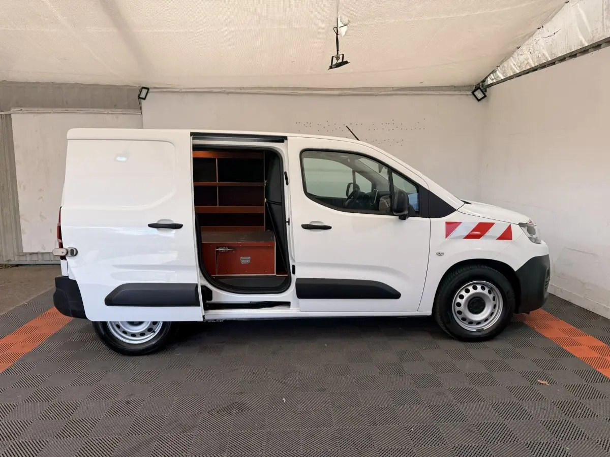 Vue latérale droite d’un Citroën Berlingo blanc 2019 avec porte coulissante ouverte et marquages rouges sur l’aile avant.