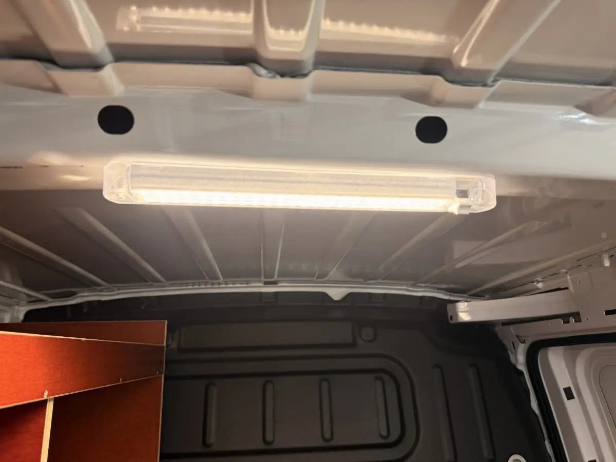 Intérieur du coffre d’un Citroën Berlingo blanc 2019, vue du plafond avec éclairage LED et aménagement bois latéral.