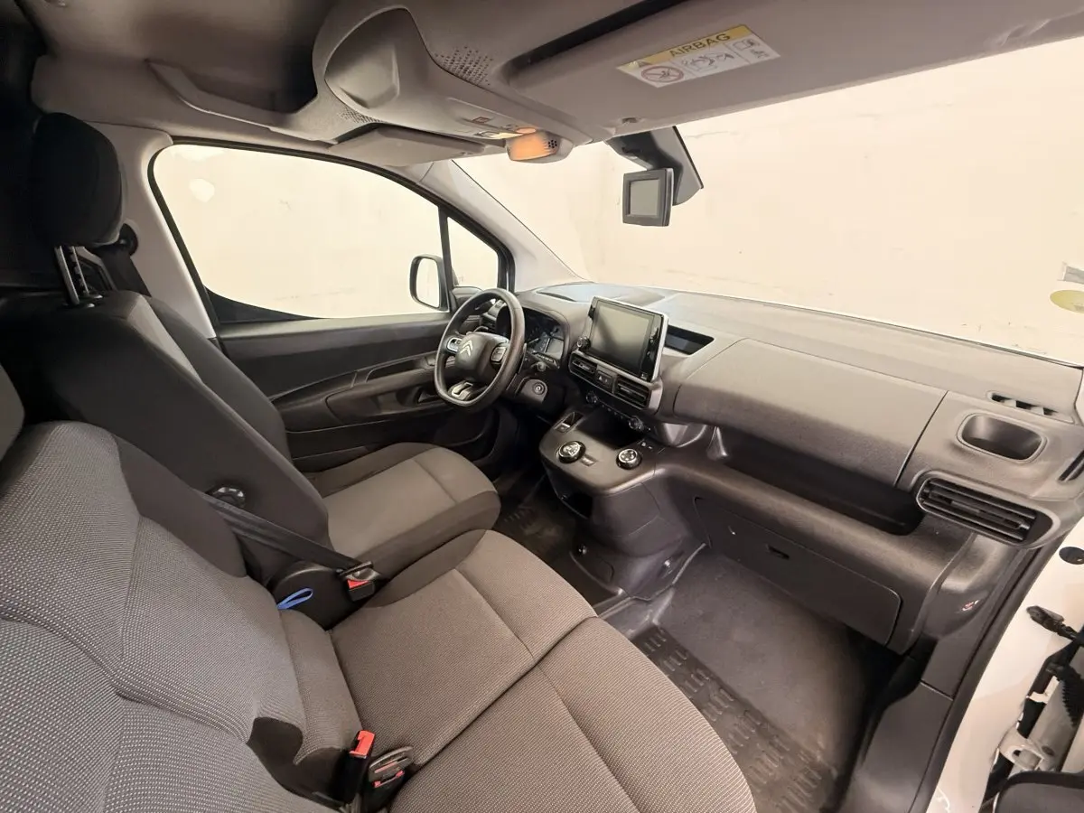 Vue intérieure côté conducteur du Citroën Berlingo blanc 2019, montrant le tableau de bord et les sièges gris.