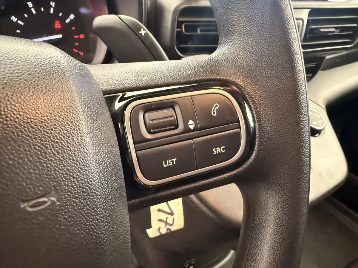 Gros plan sur les commandes multifonctions noires du volant du Citroën Berlingo 2019, intérieur noir.