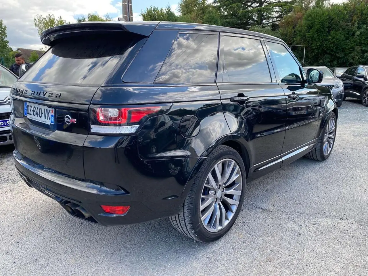 Range Rover Sport noir vu en 3/4 arrière droit, avec jantes 22 pouces et vitres arrière teintées.