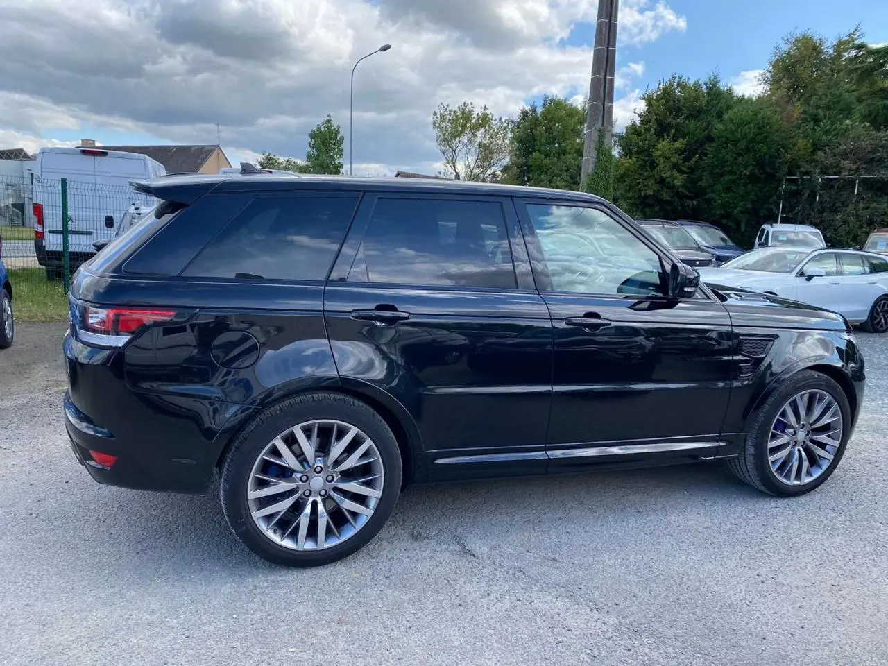 Profil côté gauche du Range Rover Sport noir 2016 avec jantes 22 pouces et vitres arrière teintées.