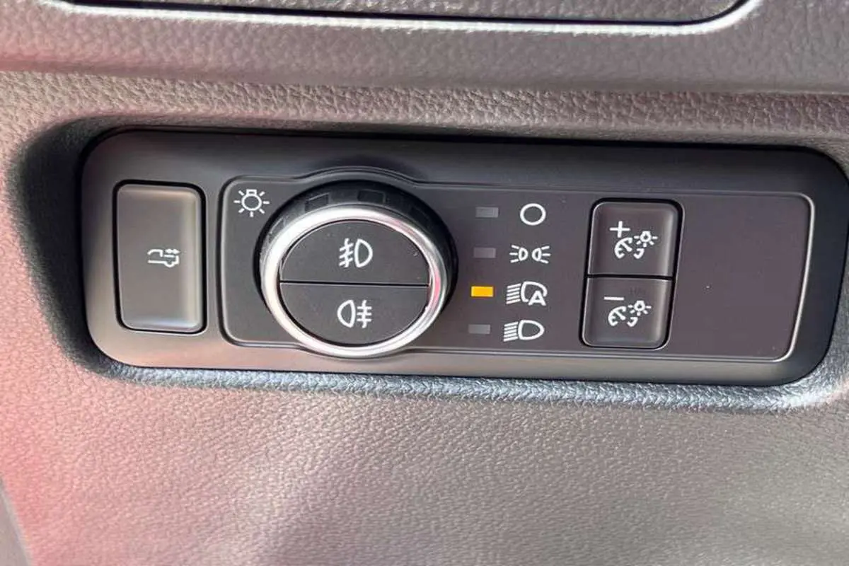 Gros plan sur les commandes d’éclairage du Ford Ranger Raptor 2025 en gris météore, avec bouton rotatif et réglages lumineux.
