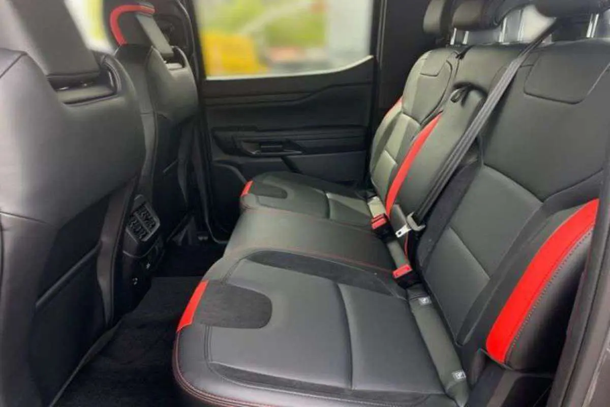 Vue intérieure arrière du Ford Ranger Raptor 2025 avec sièges noirs et inserts rouges contrastants.
