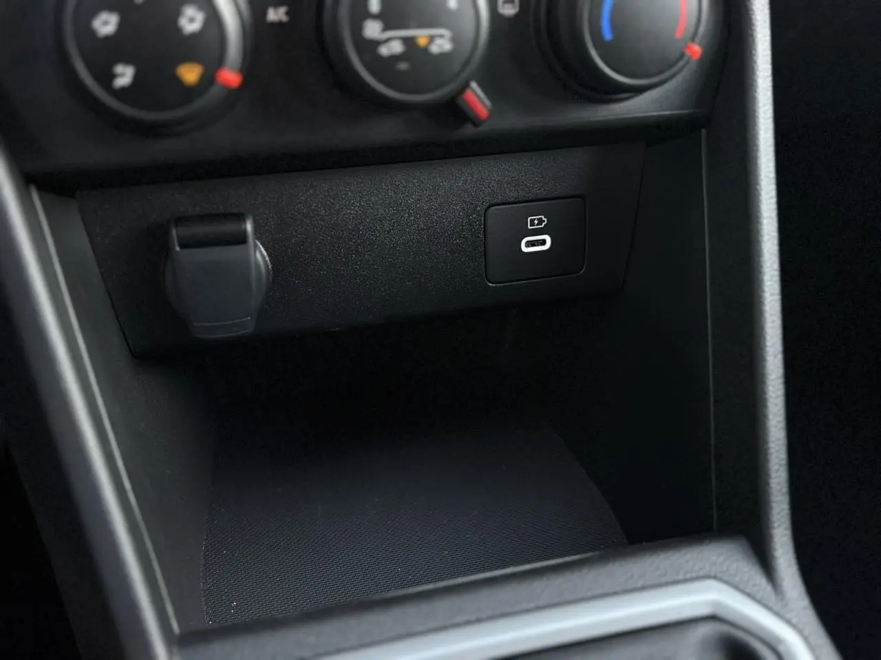 Gros plan sur la console centrale noire de la Dacia Sandero Stepway 2025 montrant la prise USB-C de recharge.